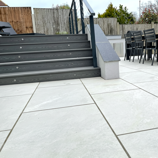 Outdoor patio area with steps leading to a deck and outdoor furniture.